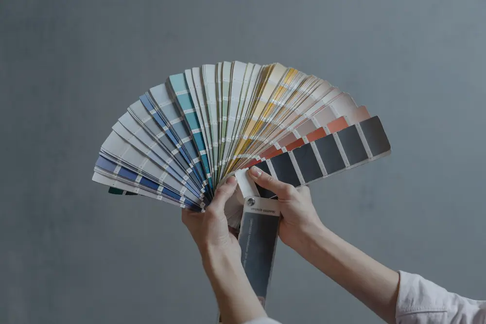 Hand holding open a fan deck of paint colors