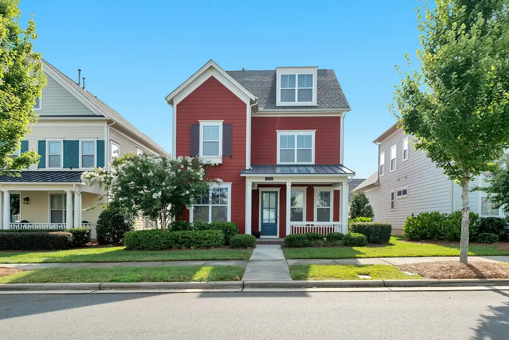 Red two-story house with white trim on a residential street