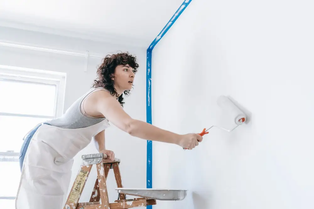 Painter rolling white paint onto an interior wall
