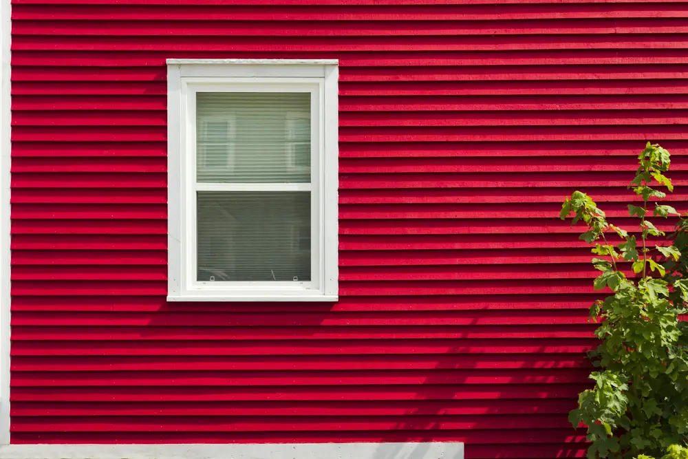 Red lap siding around a white window